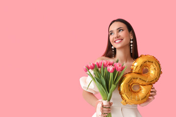 Stylish young woman with tulips and balloon in shape of figure 8 on pink background. International...