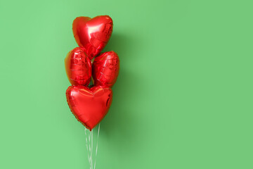 Beautiful heart-shaped balloons for Valentine's Day celebration on green background