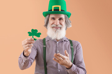Senior man in green hat with clover on beige background. St. Patrick's Day celebration