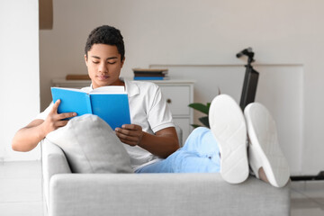 Male African-American student reading book on sofa