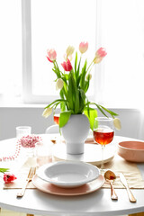 Dining table with stylish setting for International Women's Day celebration in light room