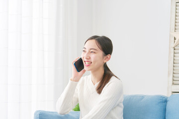 女性　スマホで電話する　リビング