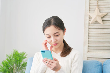 Fototapeta premium 女性 スマホ 悩む リビング