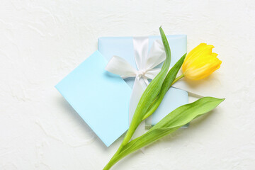 Blank greeting card for International Women's Day, gift box and tulip on light background