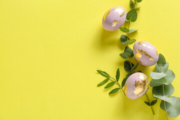 Beautiful Easter eggs and eucalyptus branches on color background