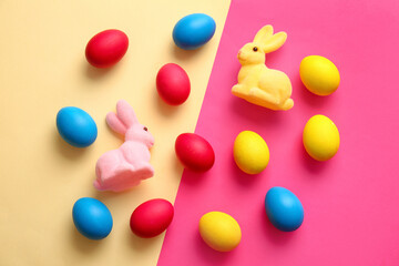 Multicolored Easter eggs and bunnies on color background