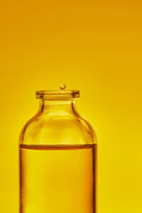 Bottle of cosmetic oil. A flying drop of oil. Front view.