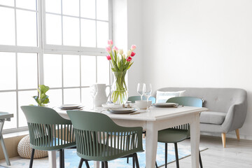 Interior of stylish room with beautiful table setting and tulips for International Women's Day celebration