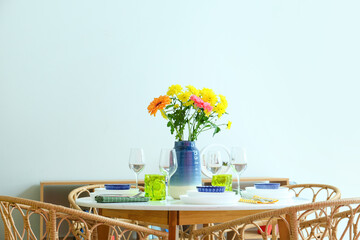 Dining table with beautiful flowers and setting for International Women's Day celebration near light wall