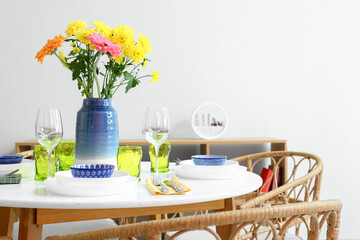 Dining table with beautiful flowers and setting for International Women's Day celebration near light wall