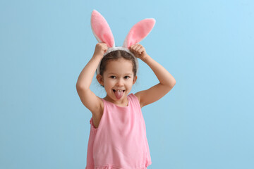 Funny little girl with bunny ears on blue background