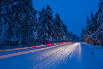 Tuinposter Dangerous road conditions, driving a car at night on icy snow covered winter road in the Arctic Circle in Lapland, Finland © Matthew