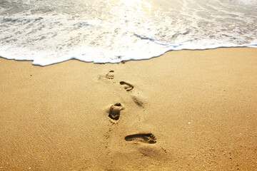 footprints on sand beach before the sea erasesthem