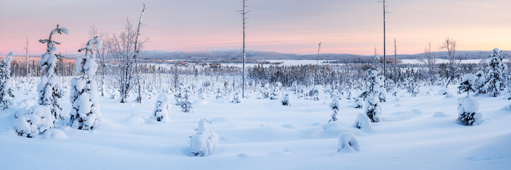 Frozen snow covered lake in the winter landscape in Lapland at sunset inside the Arctic Circle in...