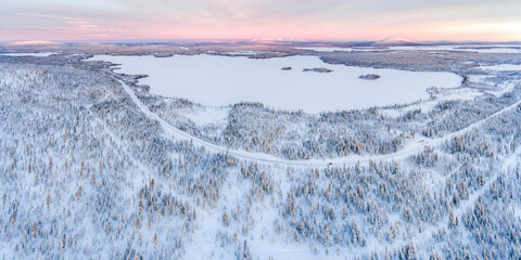 Aerial of Snow covered lake and forest winter landscape showing amazing Lapland scenery in Scandinavia in Finland drone