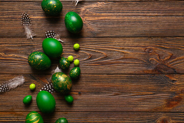 Stylish Easter eggs and feathers on wooden background