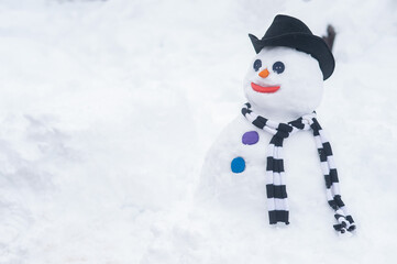 Snowman in a hat and a striped scarf. Winter fun.