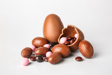 Obraz premium Different chocolate Easter eggs and delicious candies on light background
