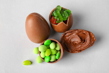 Delicious Easter eggs with candies and chocolate paste on light background