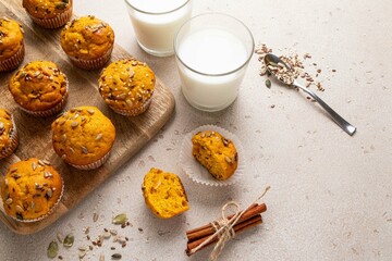 Pumpkin muffins with spices and seeds and milk on light background. Copy space. Autumn, halloween, thanksgiving baking concept.
