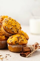 Pumpkin muffins with spices and seeds and milk on light background. Copy space. Autumn, halloween, thanksgiving baking concept. Selective focus.