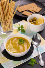 Vegetable soup with parsley and lemon in a white bowl on the table. Vertical frame.