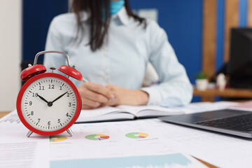 Woman at work, clock set on ten oclock in morning, work in progress