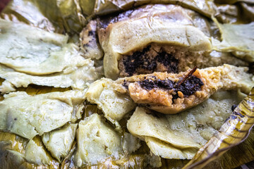 Eating Tamales in Oaxaca, Mexico. The tamale is masa filled with mole negro and chicken wrapped in a banana leaf.