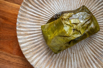 Eating Tamales in Oaxaca, Mexico. The tamale is masa filled with mole negro and chicken wrapped in a banana leaf.