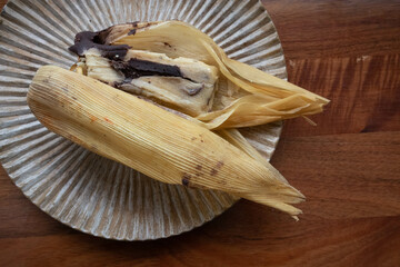 Eating Tamales in Oaxaca, Mexico. The tamal is masa filled with mole negro and chicken wrapped in corn husk.