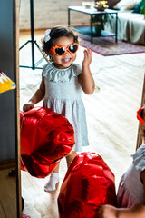 Obraz premium girl with dark, black skin color, celebrate valentine's day. heart shaped red foil balloons and glasses