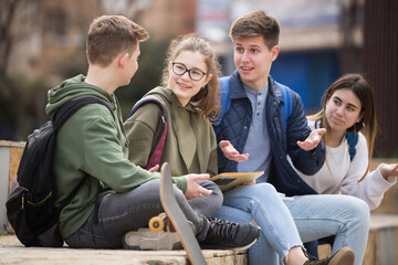 Company of teenagers are communicating on walk on the street