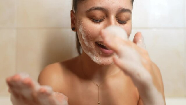 Close up cheerful woman play with foam in light bathroo imn slow motion