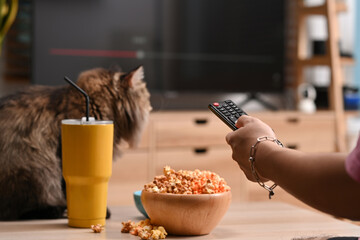 Man watching tv and eating popcorn  on couch at home.