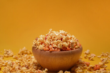 Fototapeta na wymiar Home made popcorn in wooden bowl isolated on yellow background.