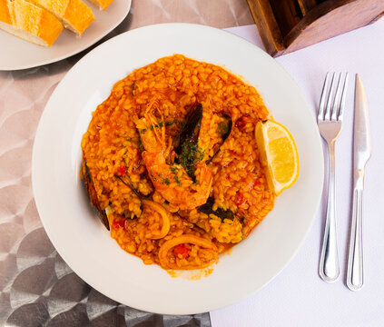 Traditional delicious dish of Spanish cuisine is paella with seafood, made from rice, vegetables, shrimp, squid and ..mussels