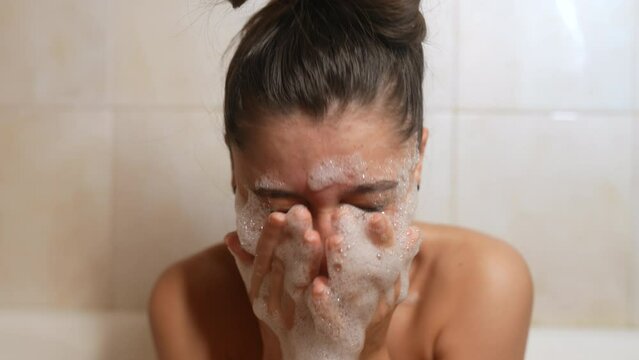Close up cheerful woman play with foam in light bathroo imn slow motion