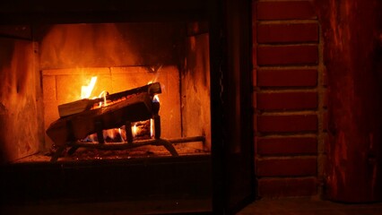 Fire in brick fireplace, firewood burning, wood blazing in cozy lodge, hut or cabin. Romantic weekend on winter holidays, fireside in warm cosy cottage house. Seamless looped cinemagraph background. - obrazy, fototapety, plakaty