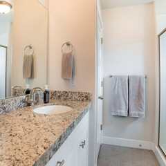 Square Bathroom interior with vanity sink and shower stall with aluminum frame