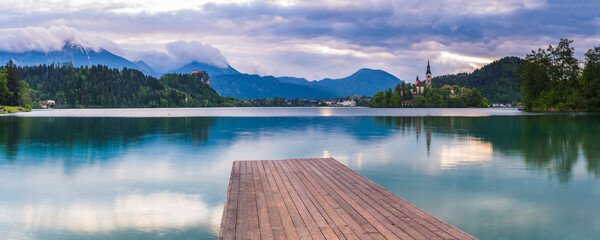 Lake Bled jetty at sunrise, showing the Church on Lake Bled Island and Bled Castle, Gorenjska...