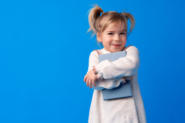 Cute little girl with book on blue background