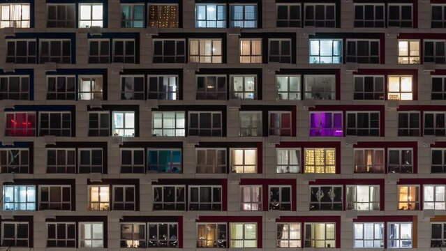 View of living apartment building windows at night. Time-lapse.