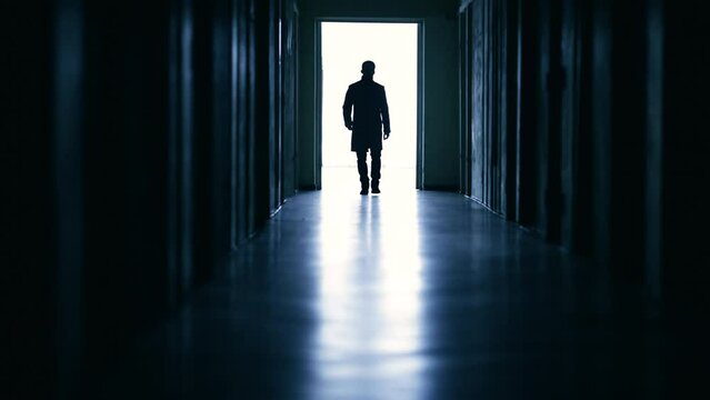 The stranger walking through the dark corridor