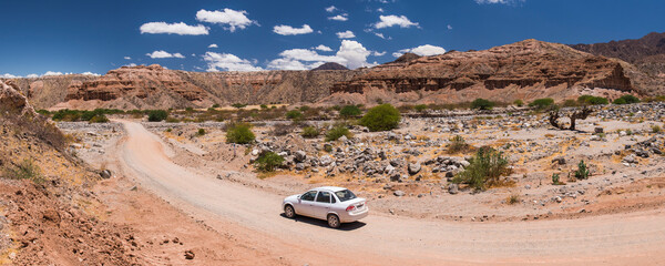 Woman driving a car on vacation on road trip through Cachi Valley Gorge (Quebrada) while on road trip holiday in the Andes Mountains, Salta Province, North Argentina, South America