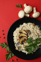 Concept of tasty food with risotto with mushrooms on red background