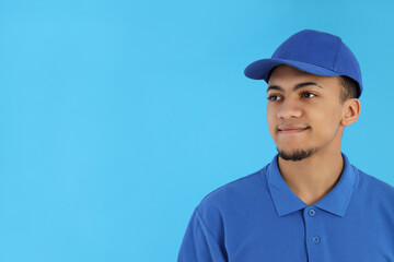 Young man in delivery uniform on blue background