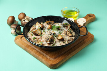 Concept of tasty food with risotto with mushrooms on mint background