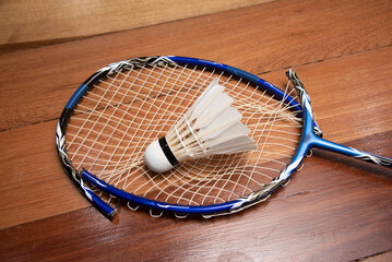 broken badminton racket and shuttlecock lay on wood table