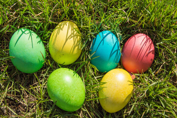 Top view of a bunch of colorful Easter eggs laid out on the green spring grass. Flat style, Easter holiday concept