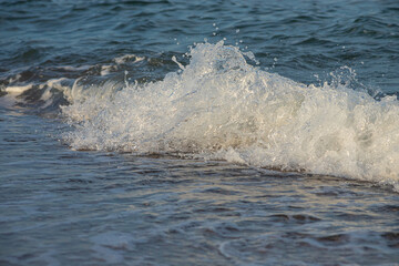 Fototapeta premium Sea waves crash against large rocks on the shore, forming large splashes